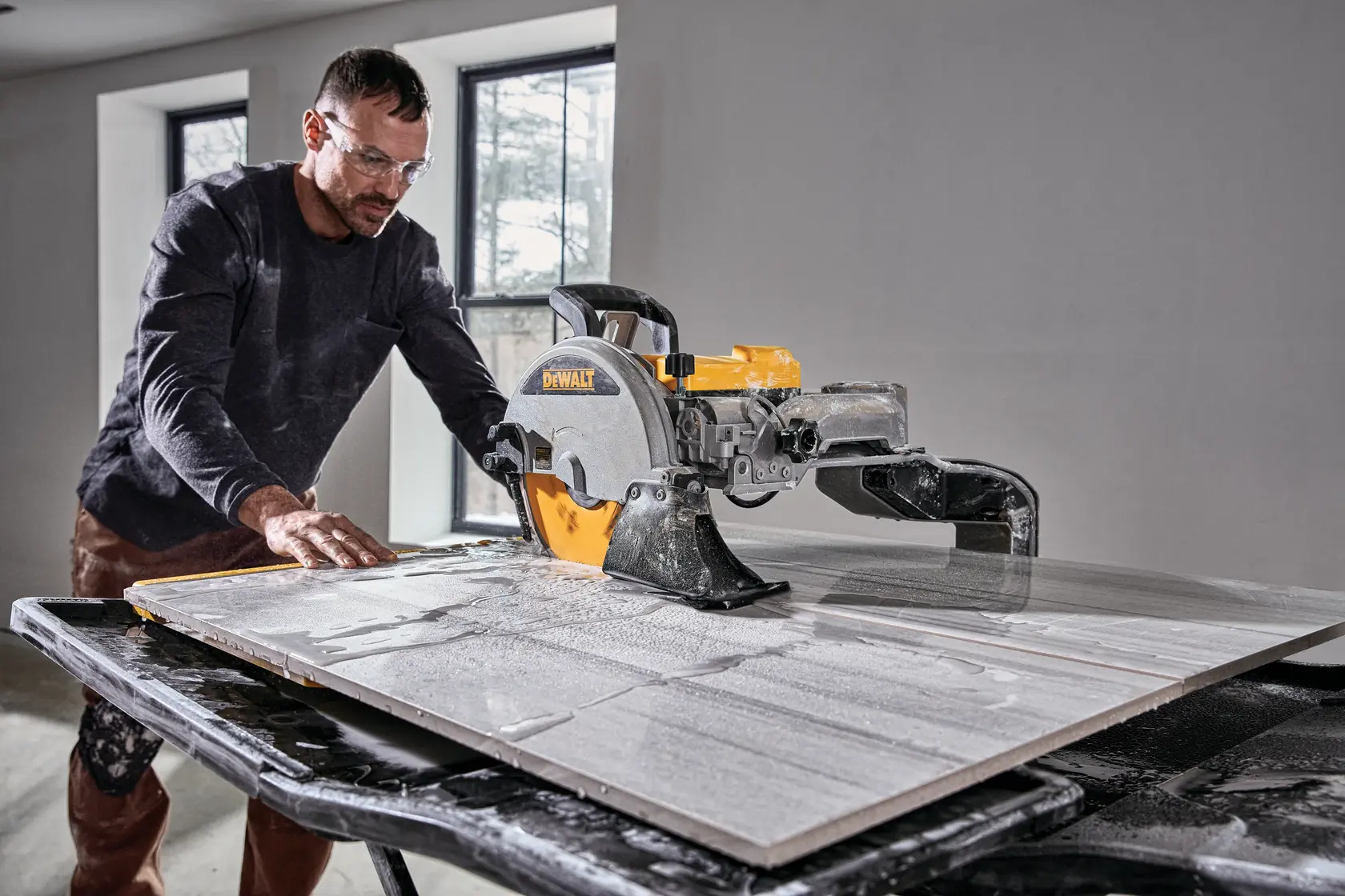 Photo of DEWALT tile saw cutting tile, SKUs D36000-QS, D36000. Worker uses saw indoors, table wet with water.