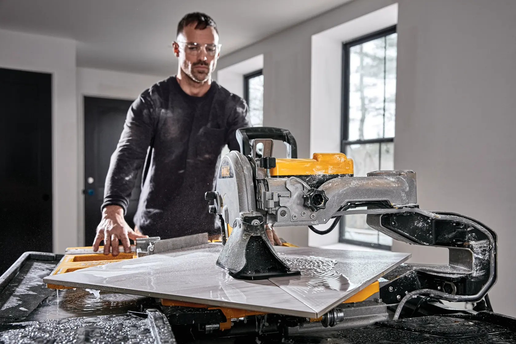 Photo of DEWALT wet tile saw in use indoors, SKUs D36000-QS, D36000, with water on surface, cutting tile.