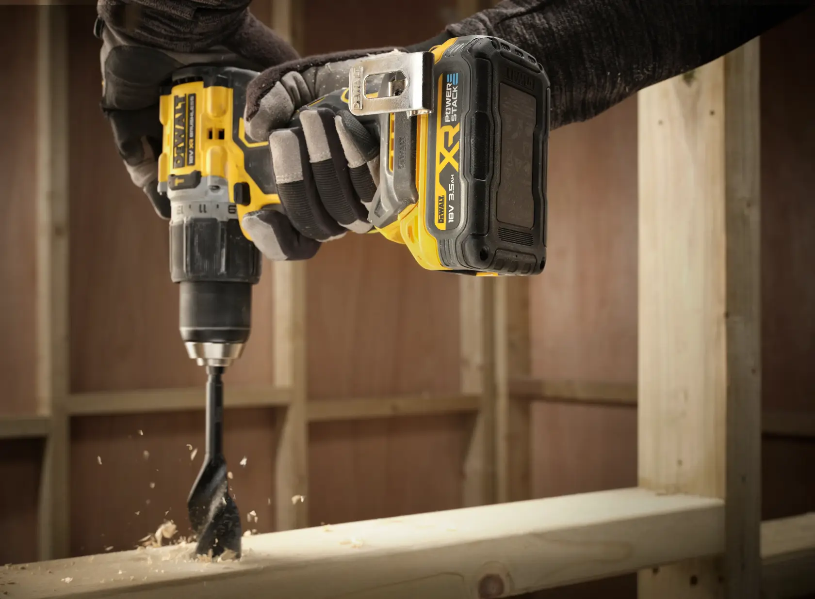 Gros plan sur une perceuse DEWALT avec batterie DCBP318, perçant du bois sur un chantier.