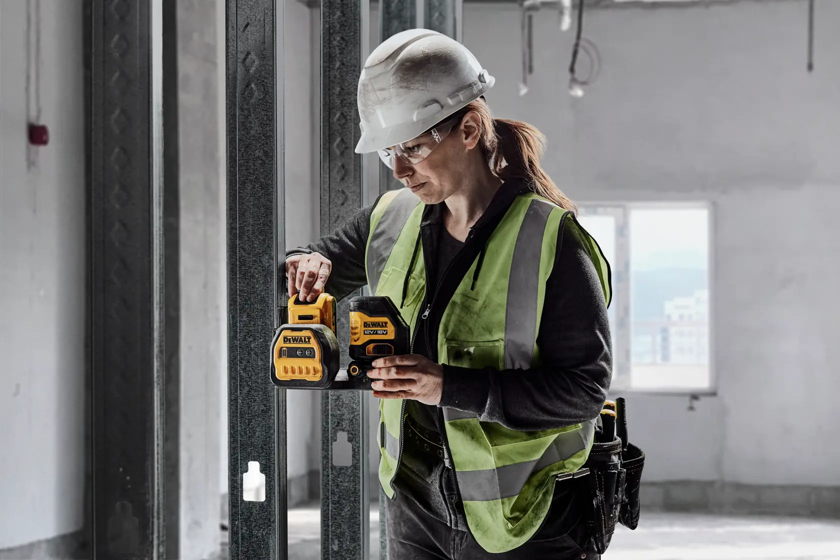 Arbeiter nutzt DEWALT DCE088D1G18-QW und DCE088D1G18 auf Baustelle. Kategorie Fotografie.