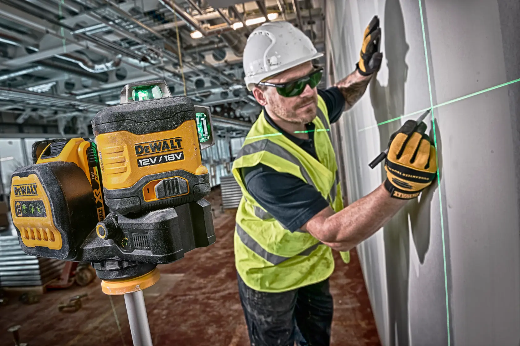 DEWALT Laser wird von einem Arbeiter mit Weste und Helm genutzt, um Linien an einer Wand zu markieren.