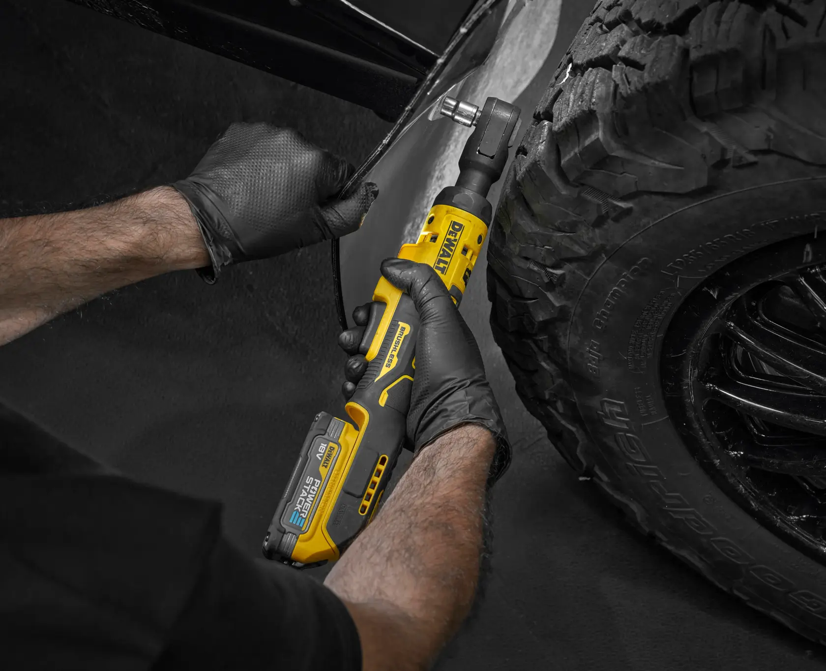 Person nutzt einen DEWALT Akku-Ratschenschlüssel am Autoreifen und trägt schwarze Handschuhe.