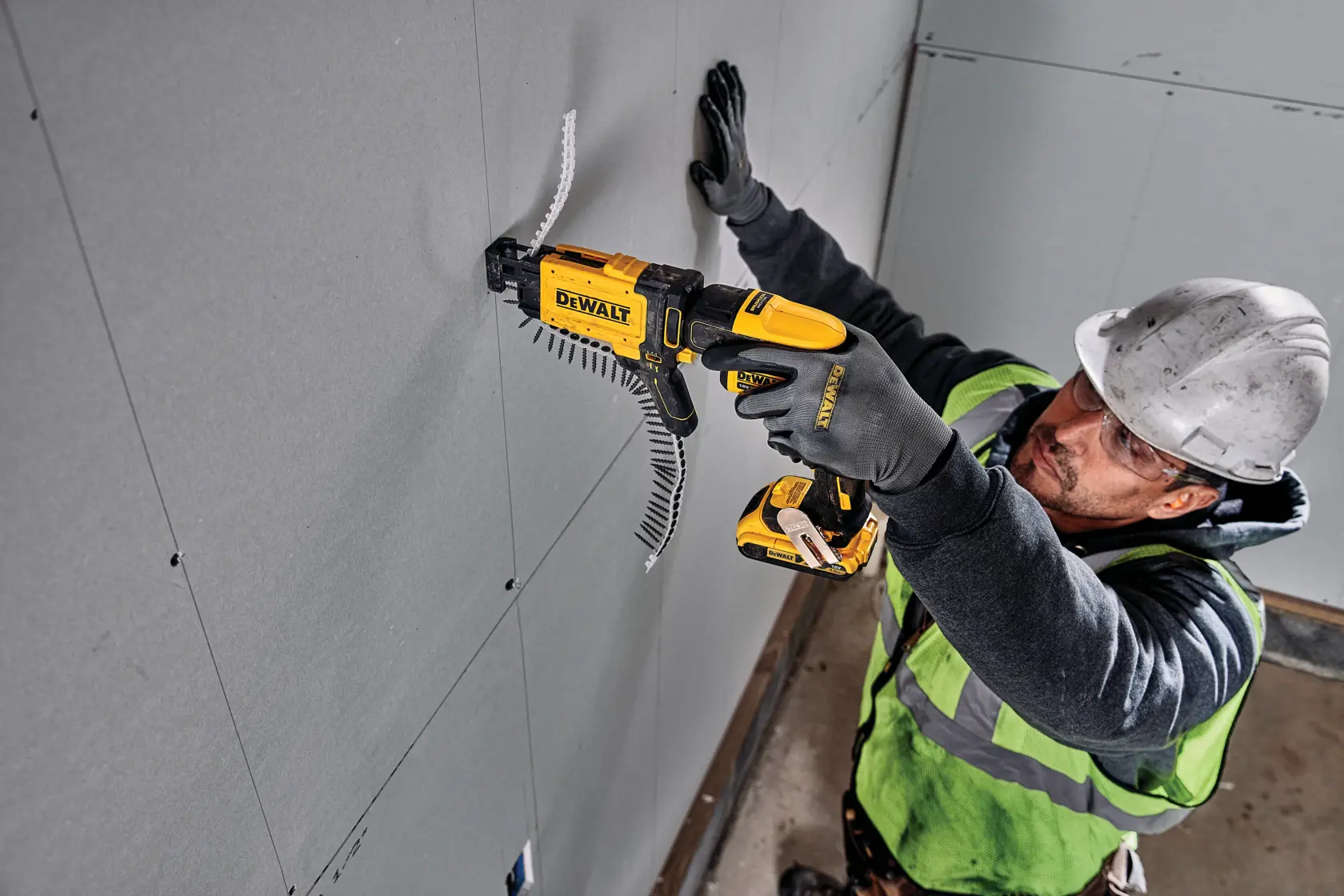 Persona usando un atornillador DEWALT DCF6202 para instalar paneles de yeso. Rostro difuminado por privacidad.