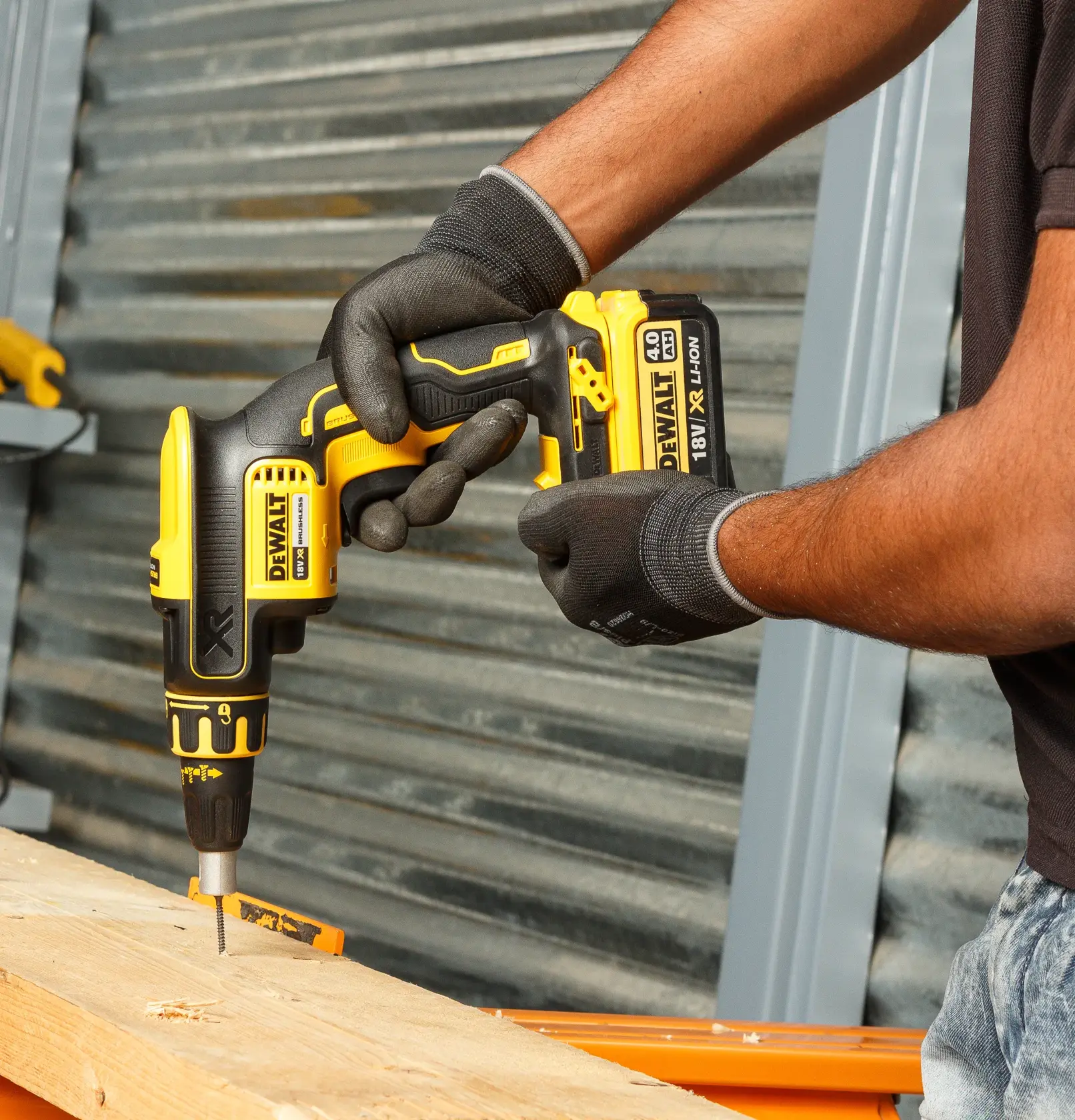 Persona utiliza DEWALT DCF620NT-XJ destornillador inalámbrico en madera, usando guantes de protección.