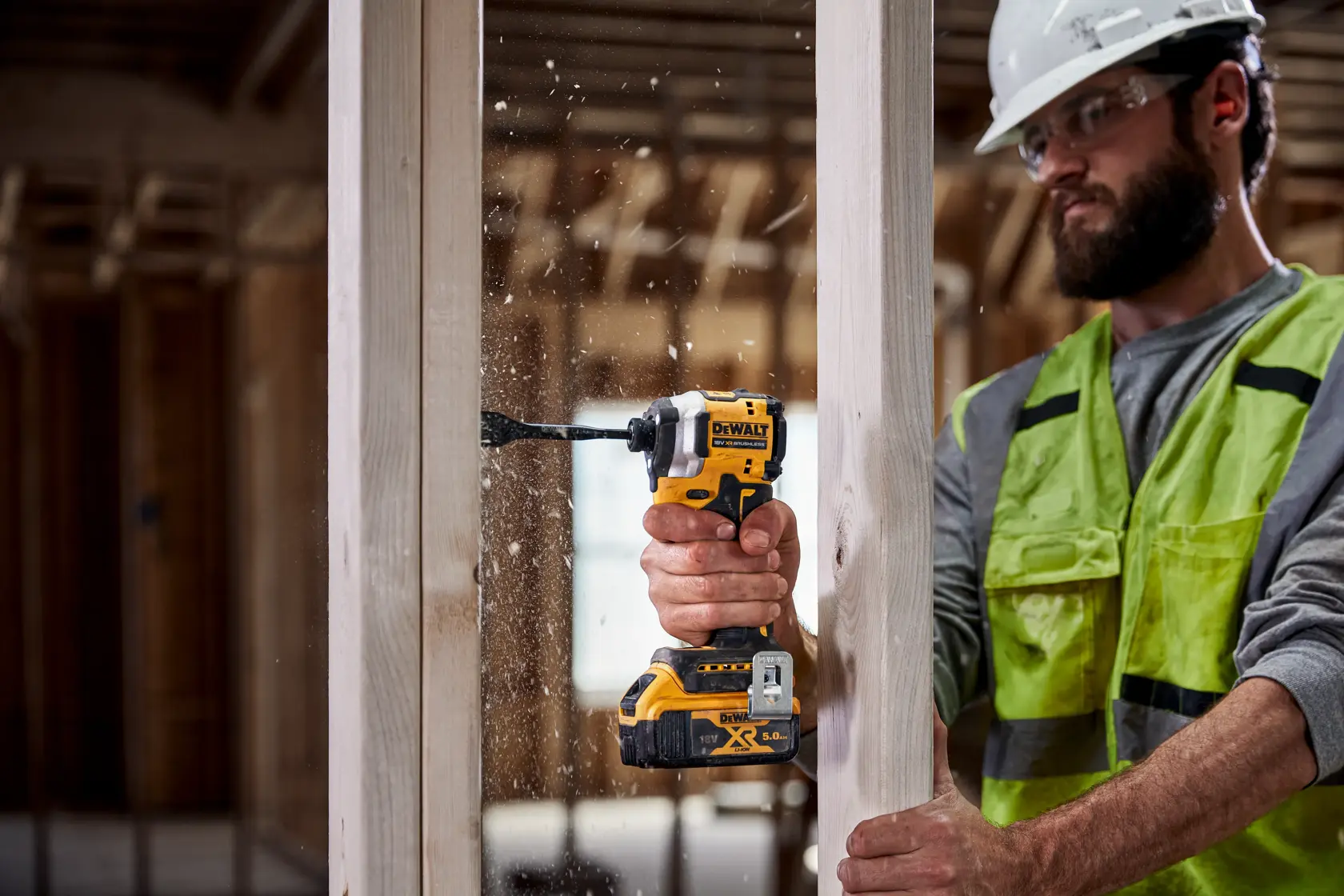 Persona usa taladro DEWALT DCF850NT para perforar un marco de madera en una construcción.
