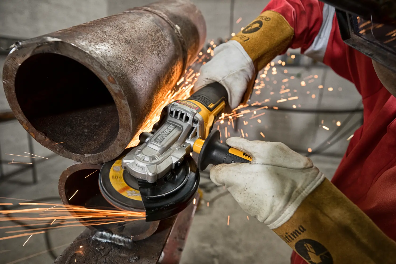 Persona usa amoladora DEWALT para cortar tubo metálico, generando chispas en entorno industrial.