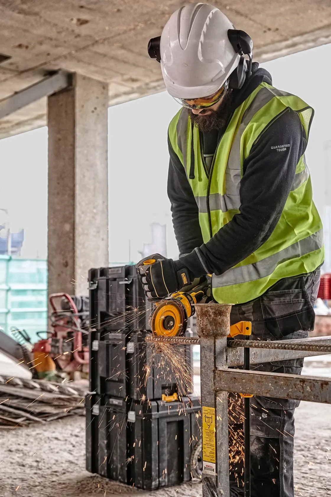 Trabajador usando amoladora DEWALT con equipo de seguridad en obra, saltan chispas de la herramienta.