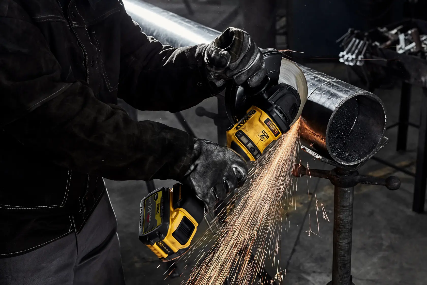 Persona corta tubo metálico con amoladora DEWALT, chispas en un entorno industrial.