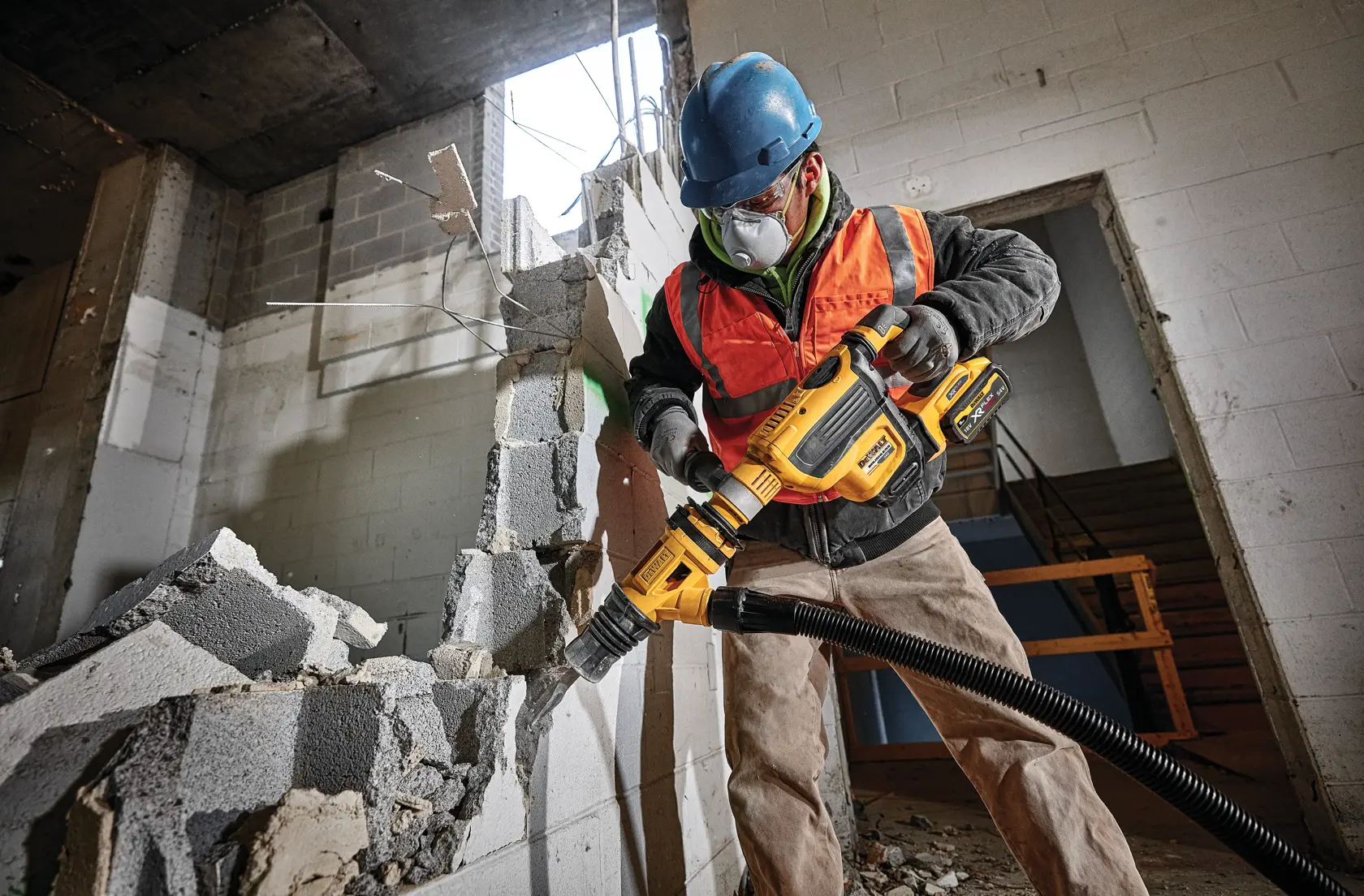 Trabajador usa herramienta DEWALT para demoler una pared de concreto en obra, lleva equipo de seguridad.