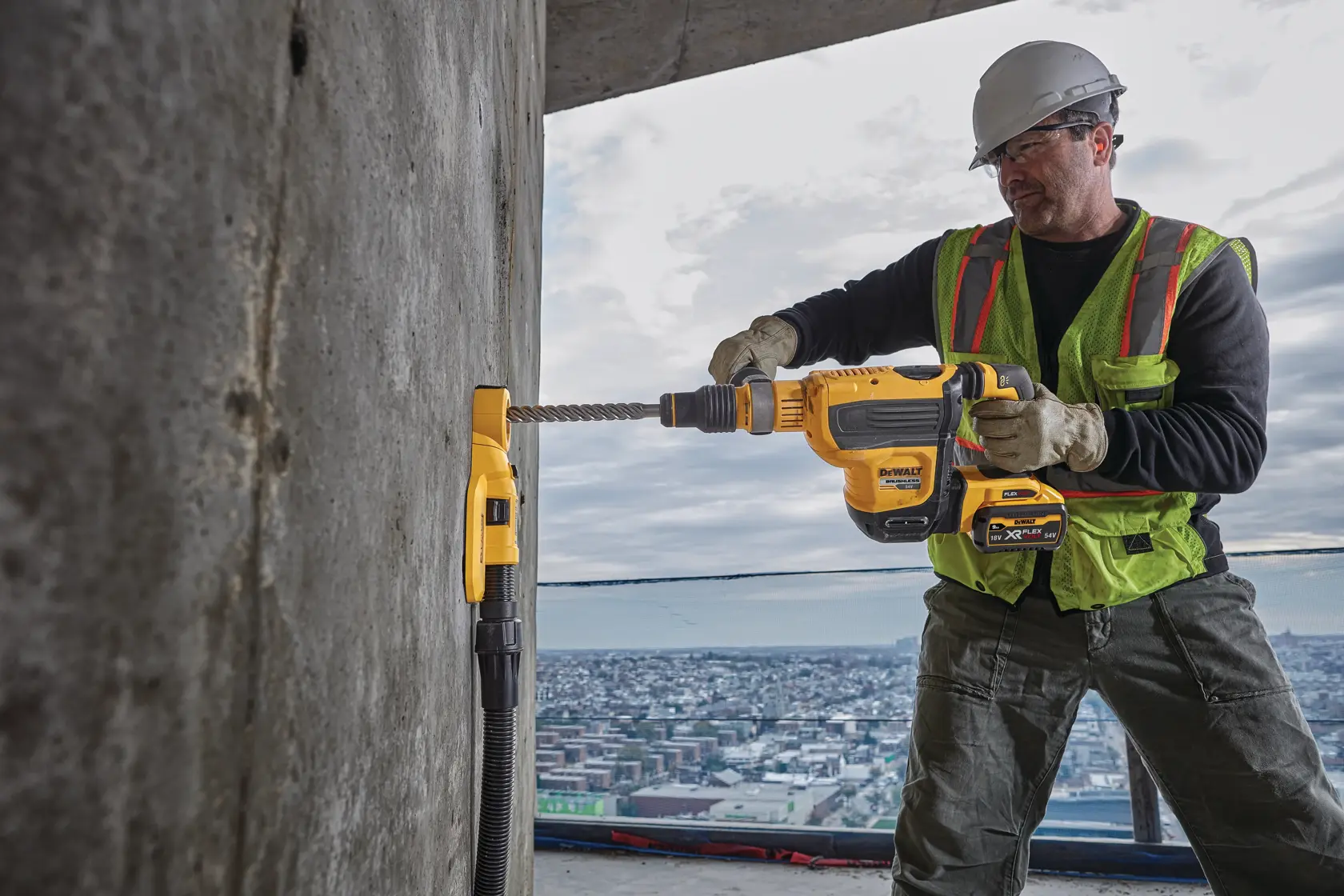 Trabajador usa martillo rotativo DEWALT inalámbrico en pared de concreto en construcción.