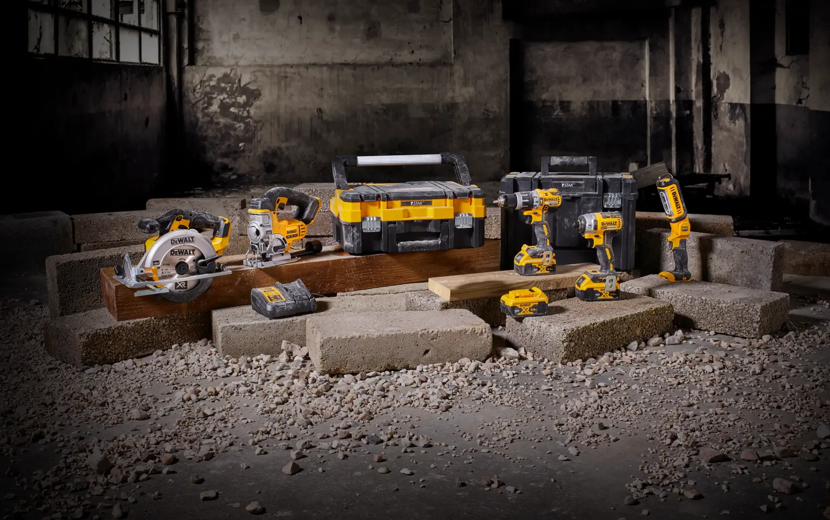 DEWALT cordless tool set with toolbox and batteries displayed on blocks in an industrial setting.