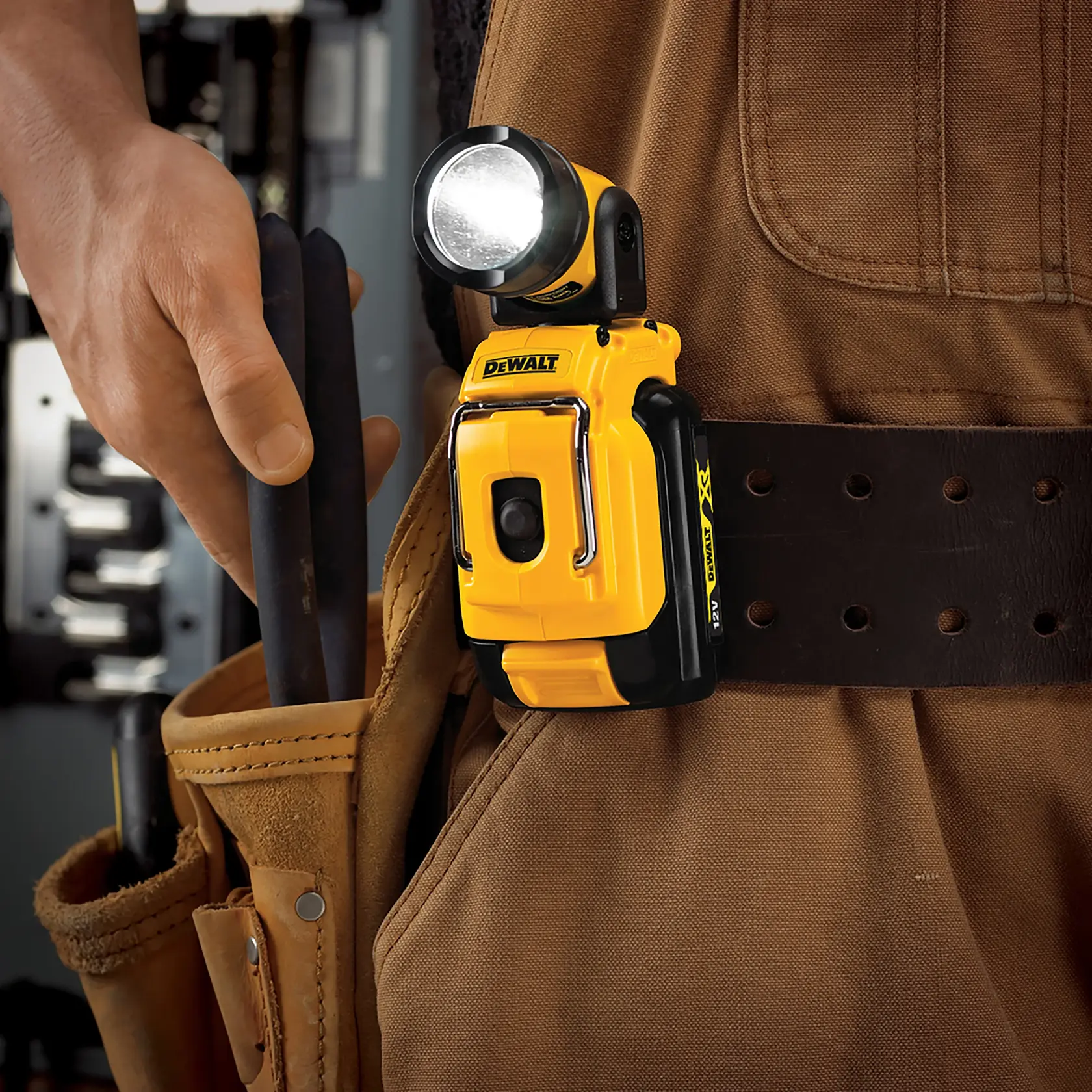 Lámpara LED DEWALT DCL510N fijada a un cinturón de herramientas sobre ropa de trabajo marrón.