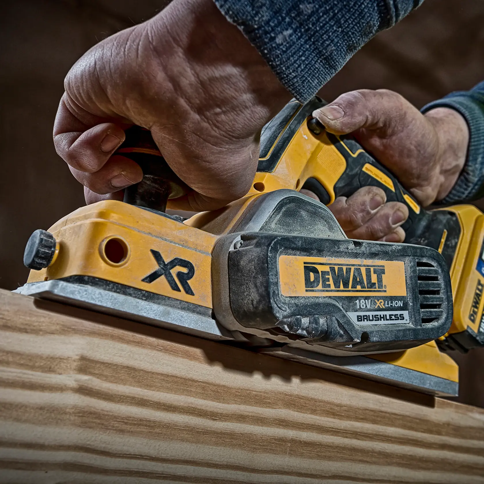 Photo of DEWALT cordless planer DCP580P2 smoothing wood, close-up, yellow with black details.