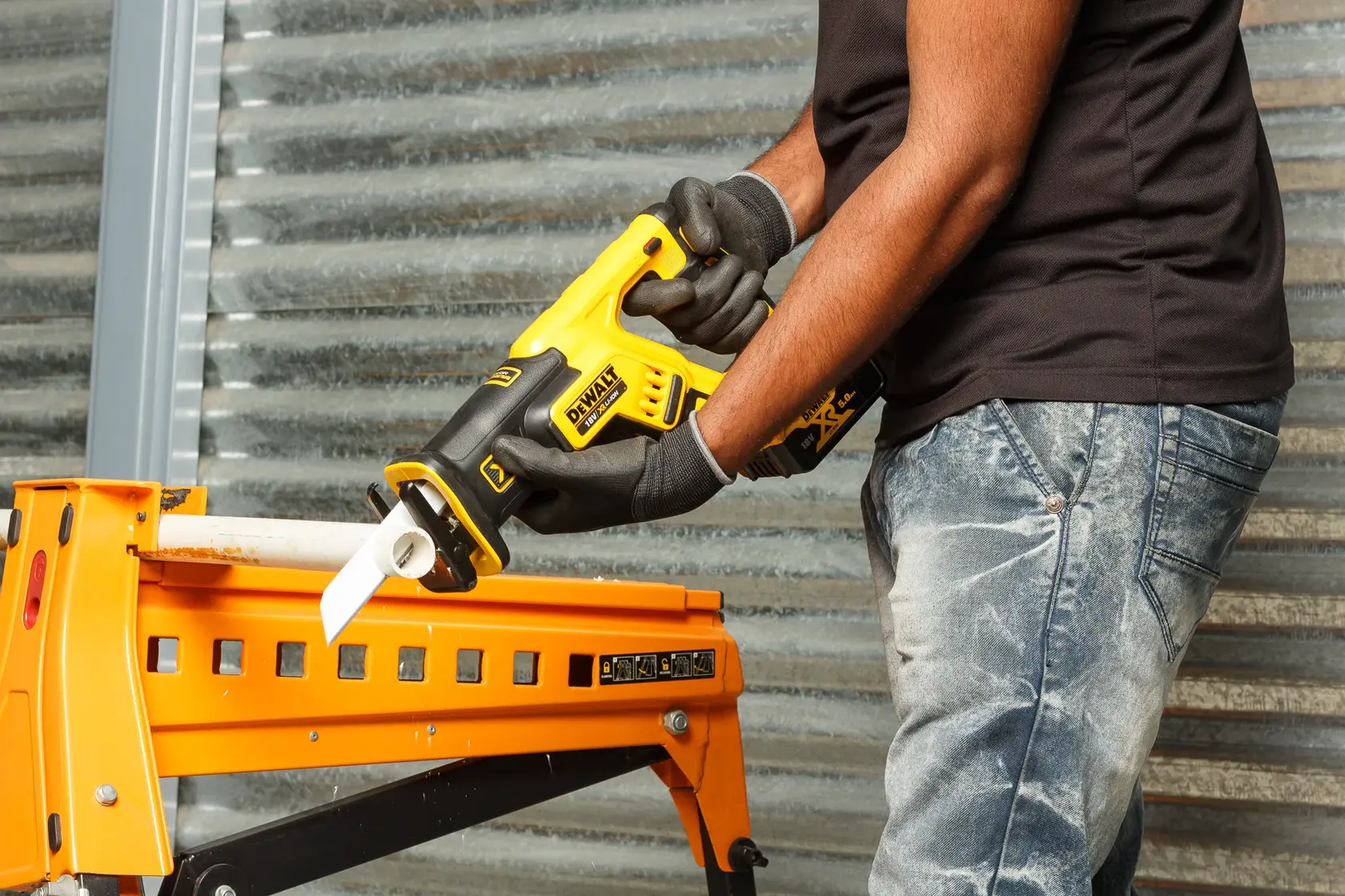 Photo of DEWALT DCS367P2 reciprocating saw cutting pipe, worker wearing gloves, product in use.