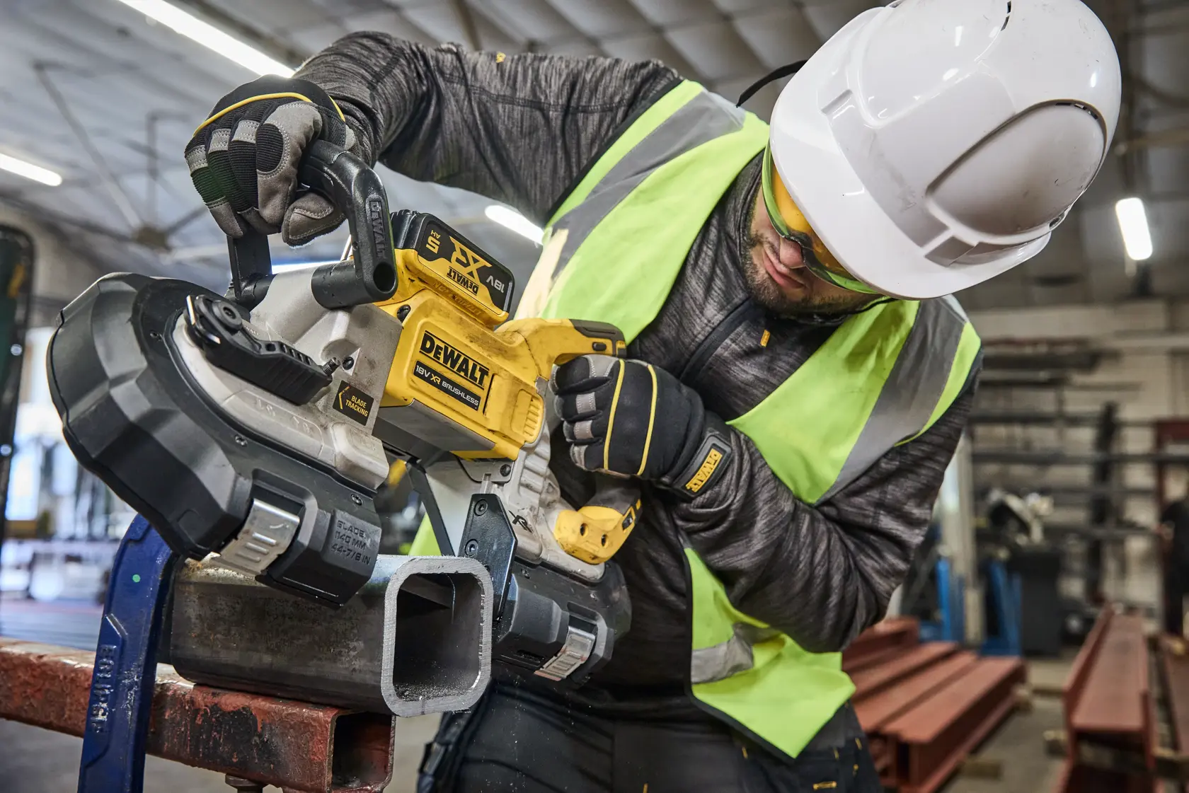 Worker uses DEWALT saw DCS374N, DCS374N-XJ to cut metal pipe in workshop.