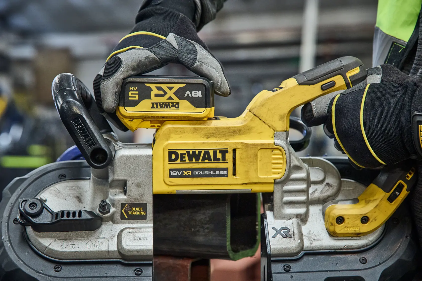 DEWALT bandsaw in use, SKUs DCS374N and DCS374N-XJ visible, held by gloved hands in workshop.