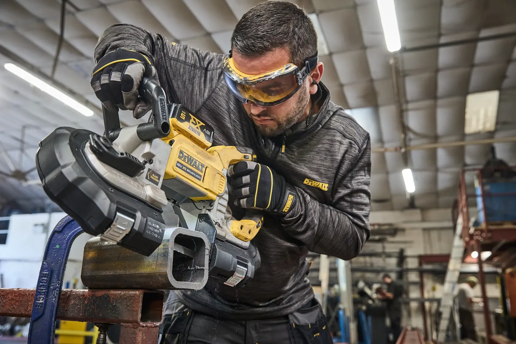 Worker uses DEWALT tool DCS374N, DCS374N-XJ to cut metal pipe in workshop.