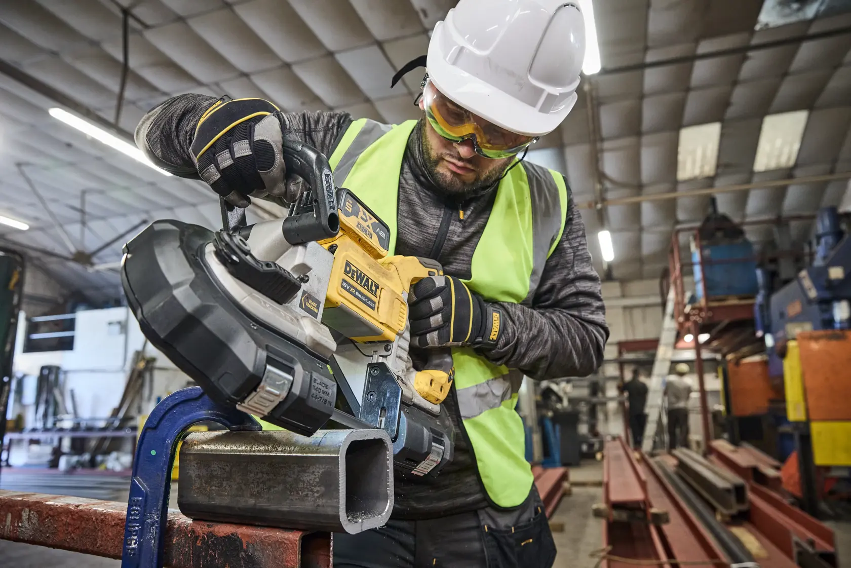 Worker uses DEWALT DCS374N, DCS374N-XJ tool to cut metal pipe in an industrial setting.