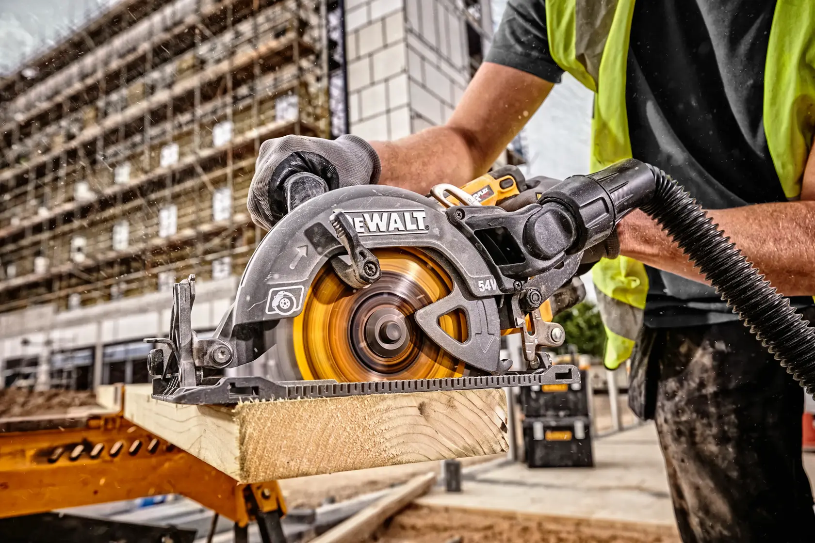 DEWALT circular saw cutting wood on a construction site, operated by a worker in safety gear.