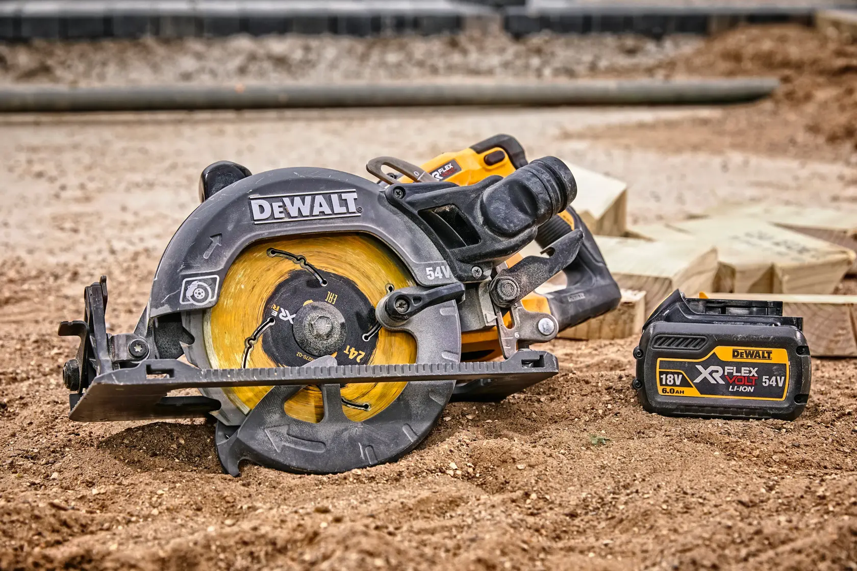 DEWALT cordless circular saw and battery on dirt, with wooden planks in background.