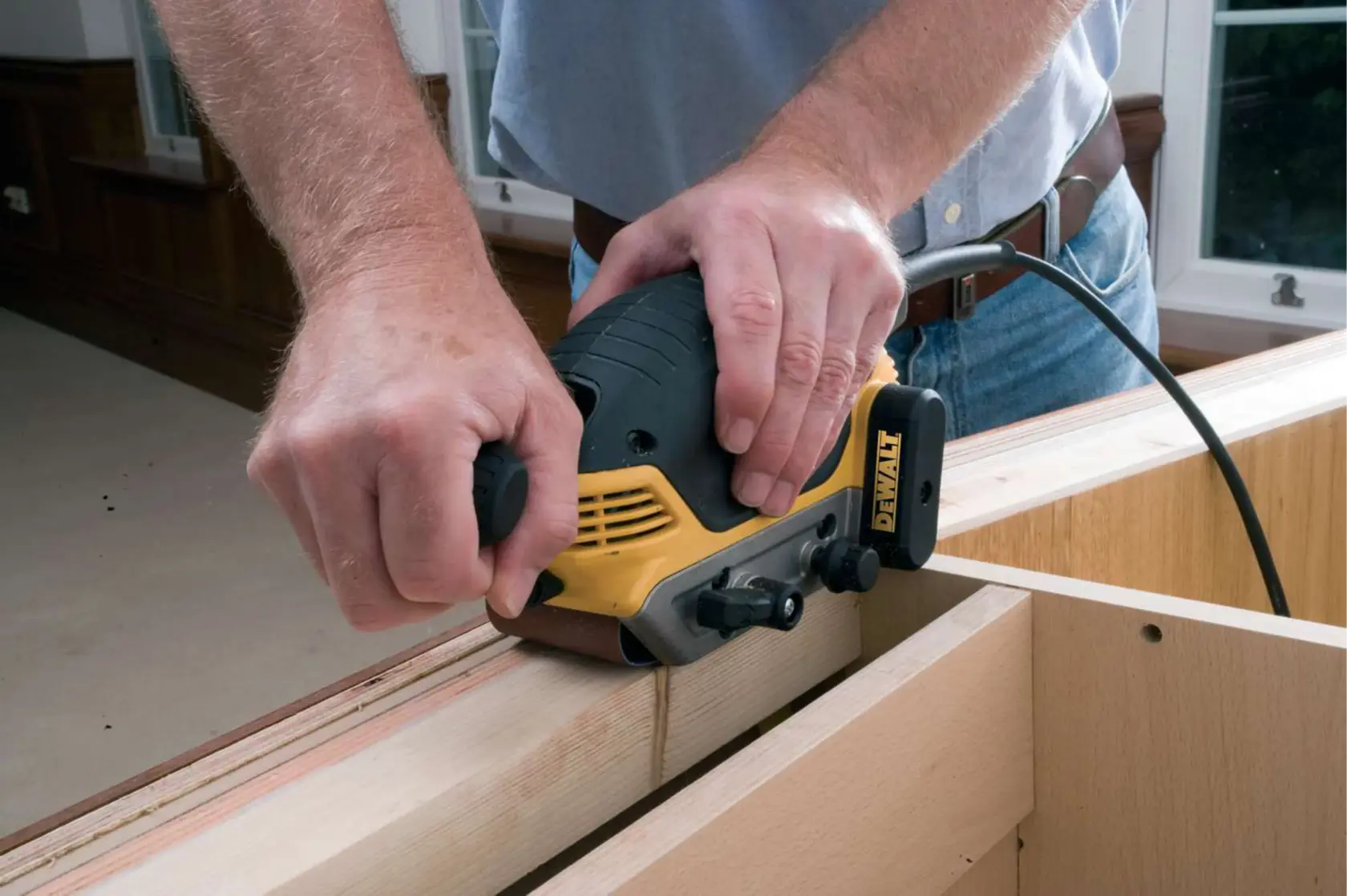 Person glättet Holz mit einem DEWALT Elektrohobel im Innenbereich.