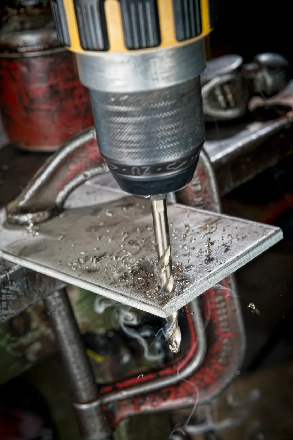 DEWALT drill bit cutting through metal sheet secured by a clamp, with metal shavings visible.