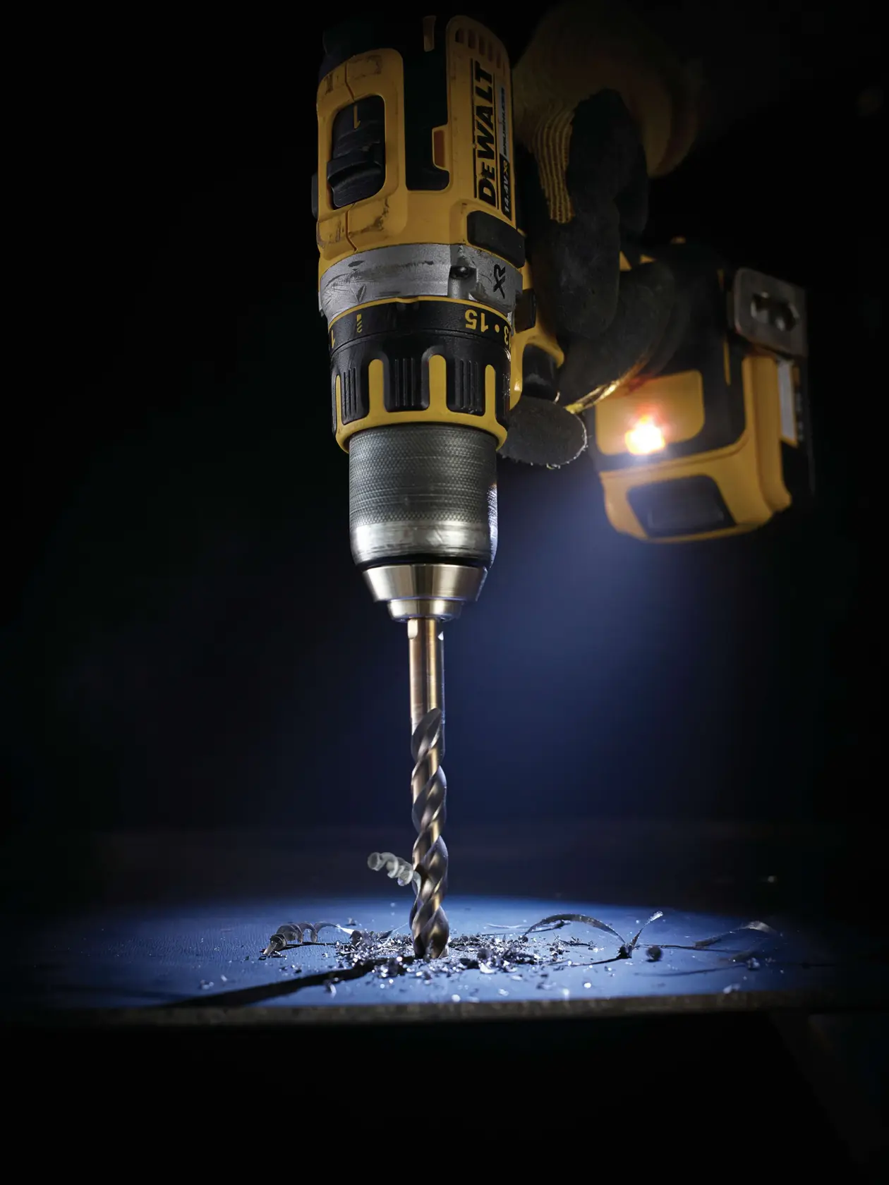 Taladro inalámbrico DEWALT perforando metal, con virutas y luz proveniente de la herramienta.