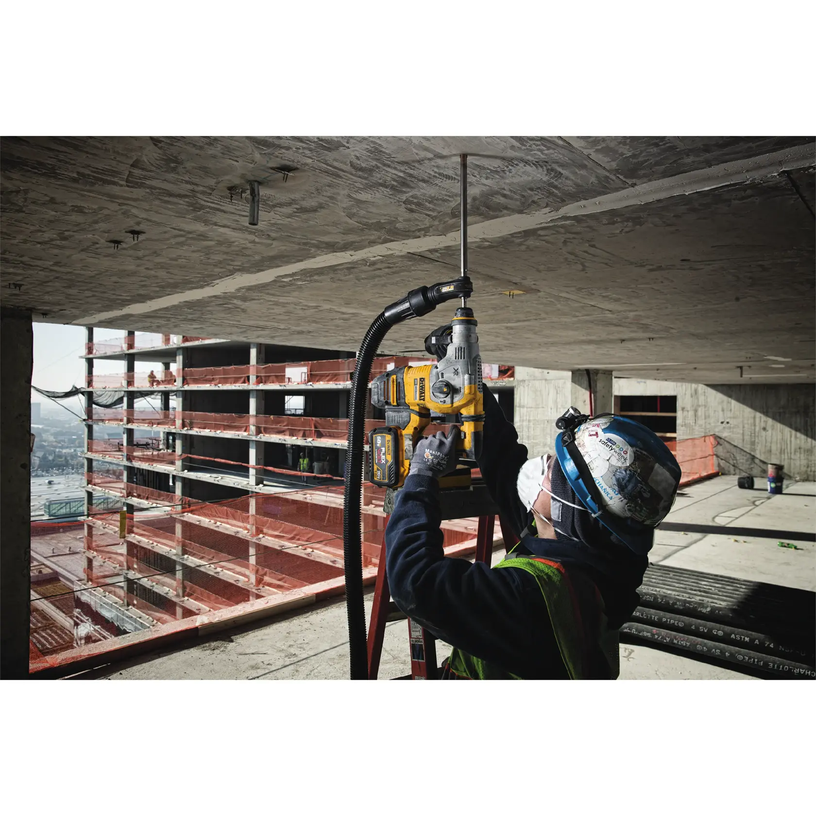 Trabajador perfora techo con herramienta DEWALT en obra, usando casco y mascarilla.