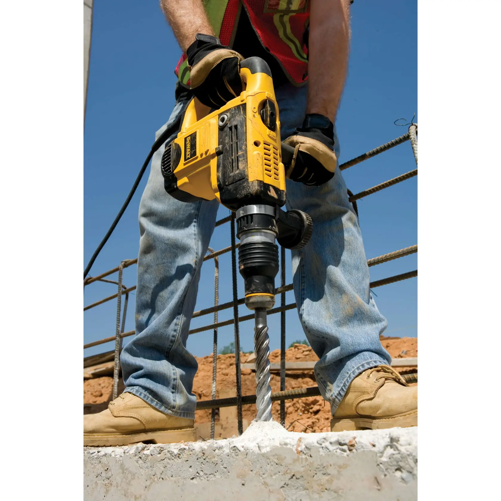 Persona usa un martillo rotatorio DEWALT para perforar concreto en una obra.