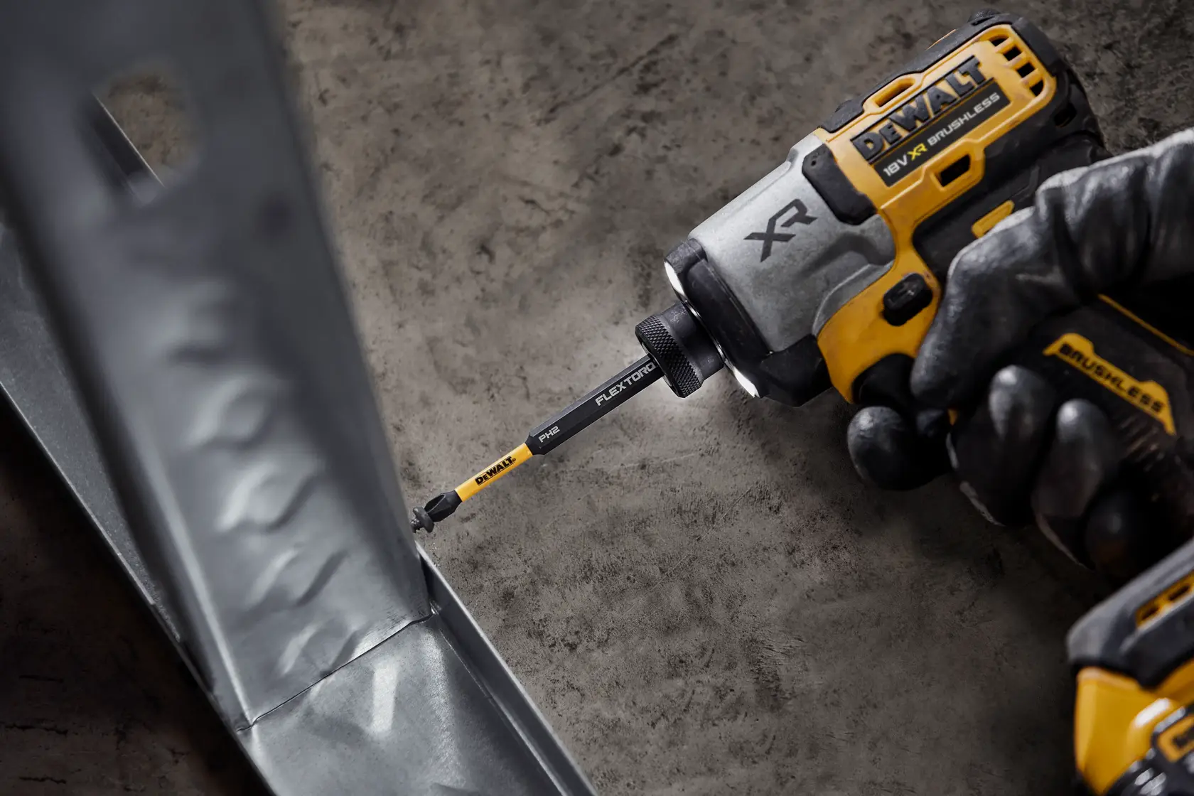 A DEWALT impact driver with FlexTorq bit is being used to drive a screw into a metal surface.