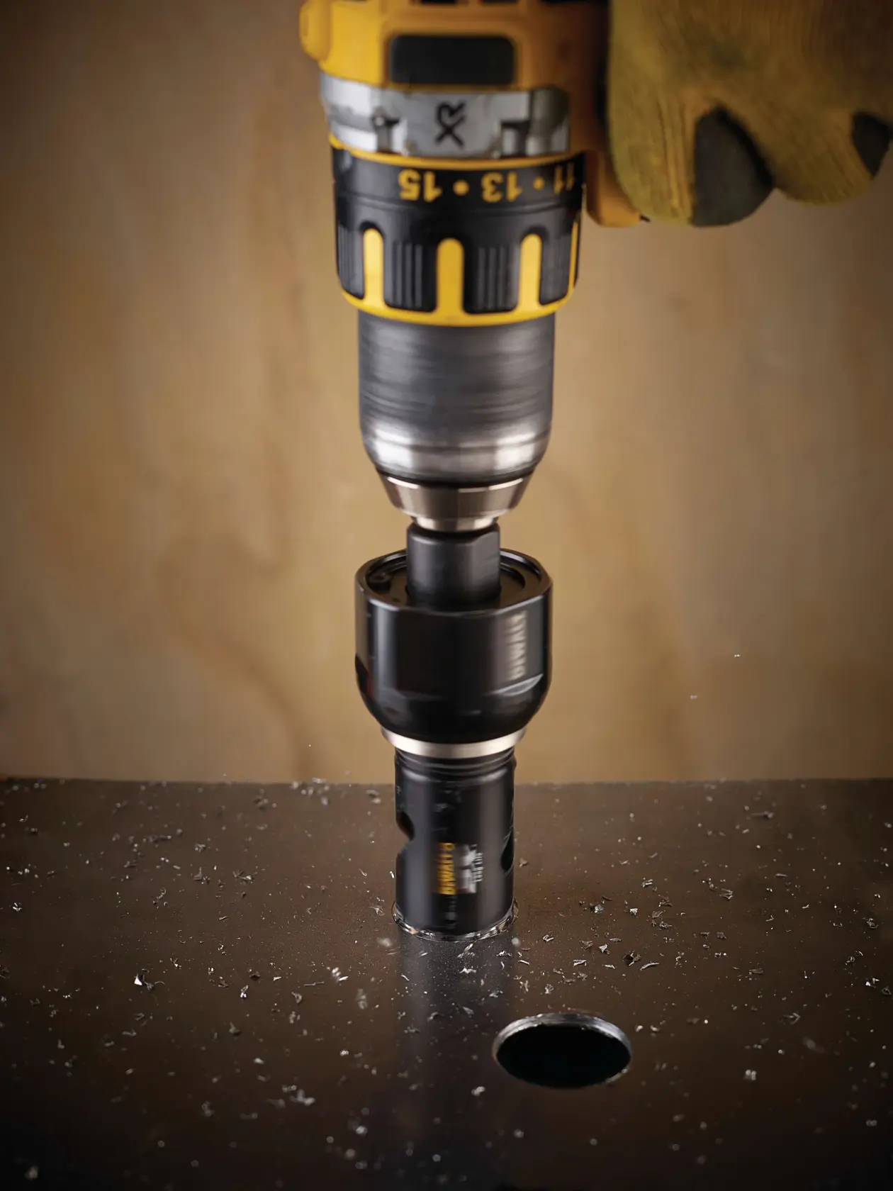 DEWALT drill with a hole saw attachment drilling through metal, creating a circular hole and metal shavings.