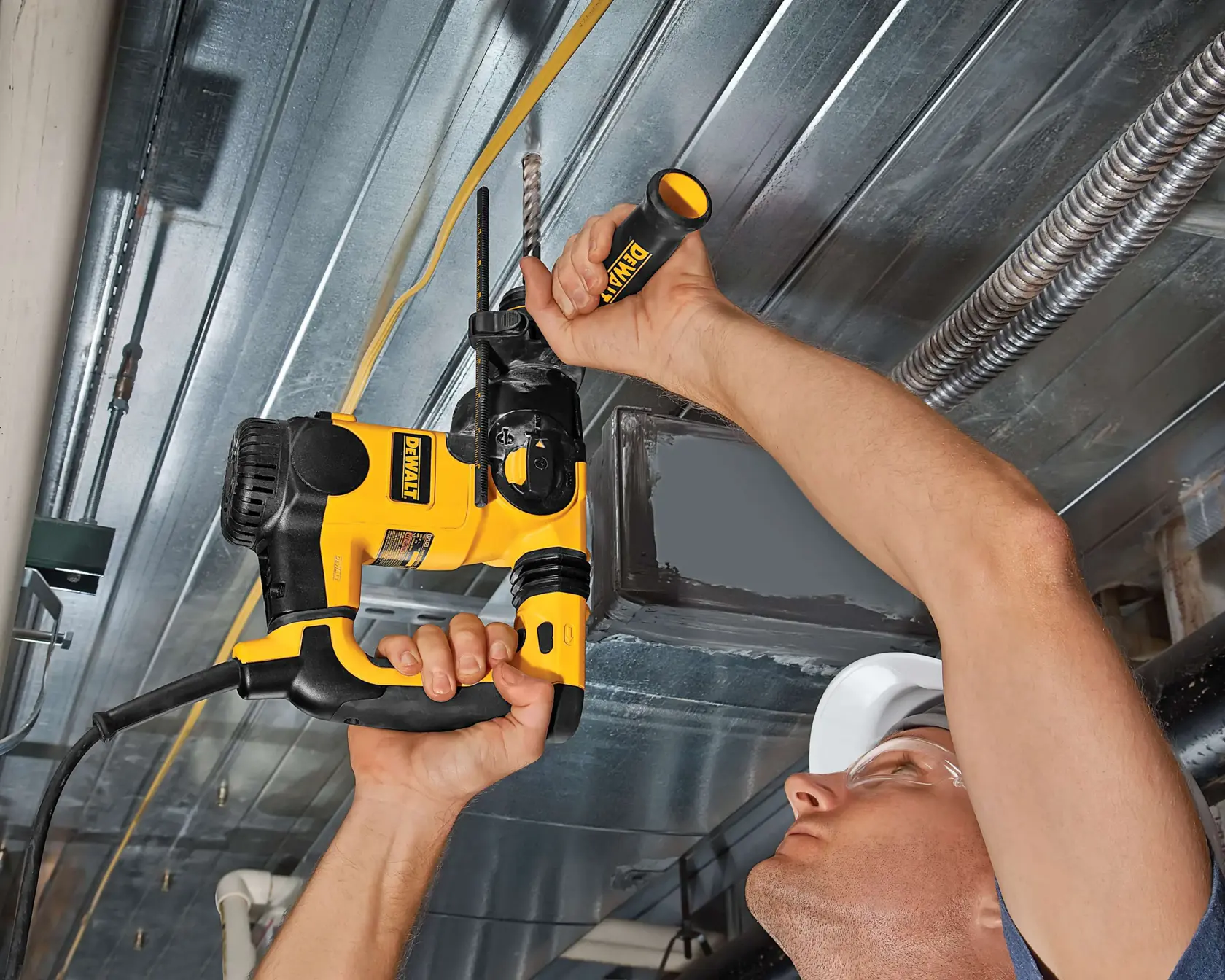 Persona utiliza un taladro DEWALT amarillo y negro para perforar un techo metálico.