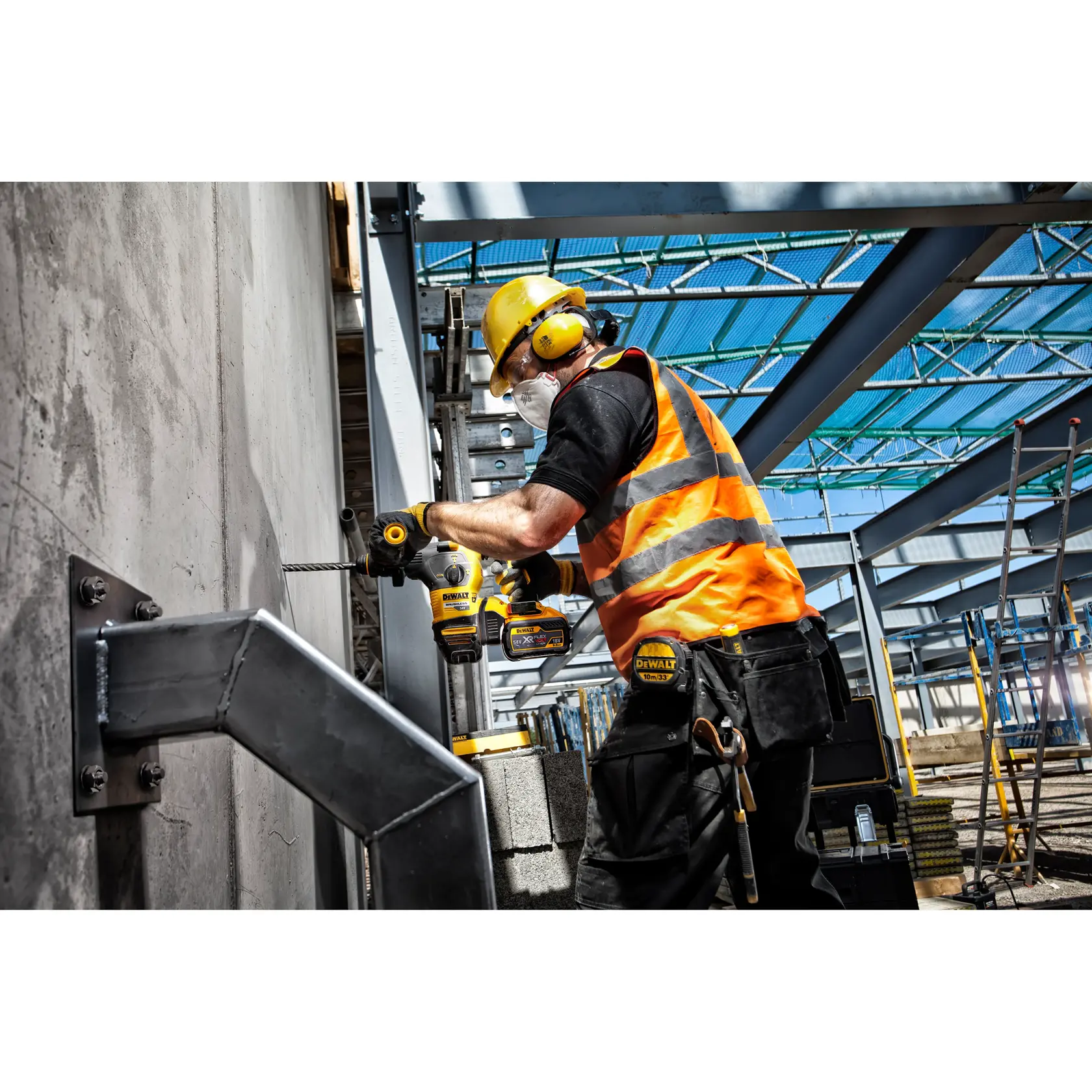 Trabajador utiliza taladro DEWALT en pared de concreto, con equipo de seguridad y chaleco naranja.
