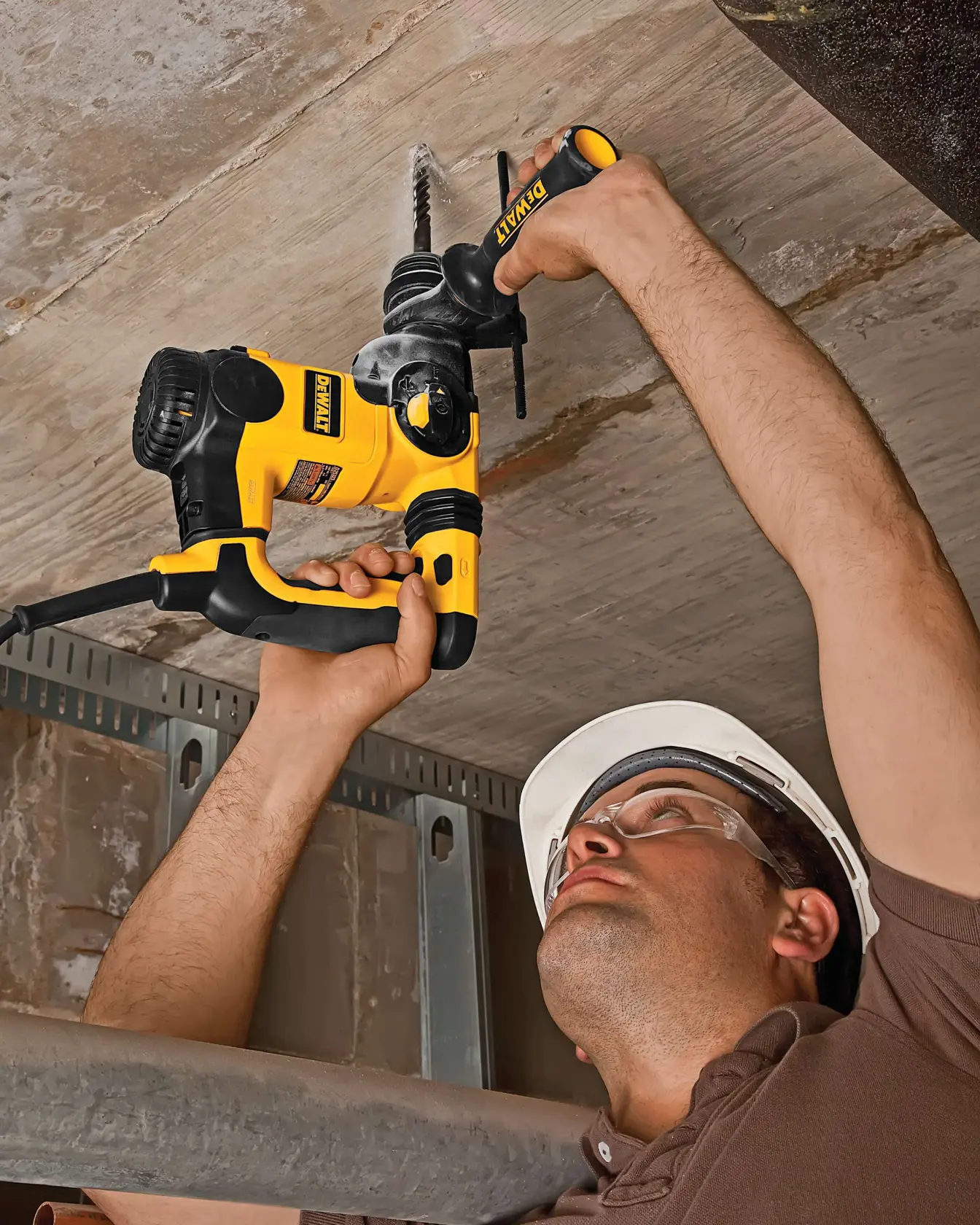 Trabajador perfora techo de concreto con un martillo rotativo DEWALT amarillo y negro.