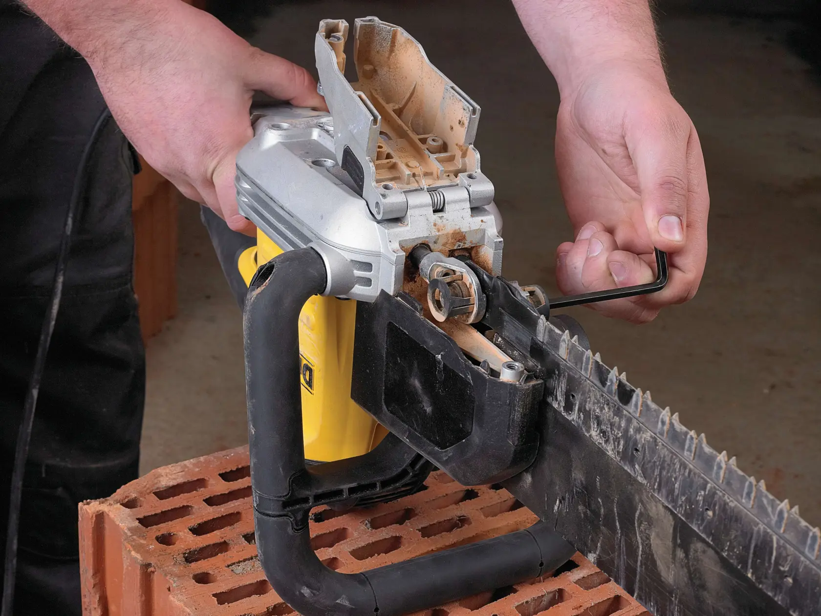 Person using a hex key to adjust a DEWALT electric masonry saw placed on a brick.