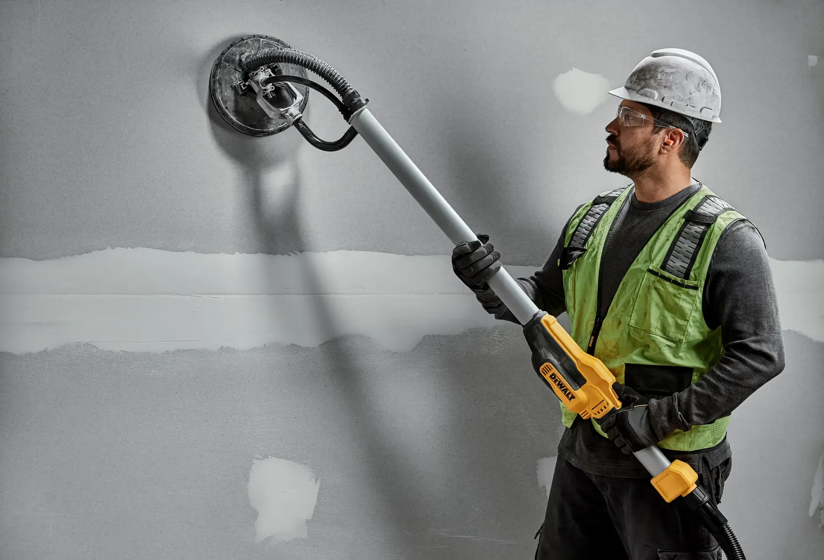 Ouvrier avec ponceuse murale DEWALT DWE7800, DWE7800-QS sur plaque de plâtre. Produit de photographie.