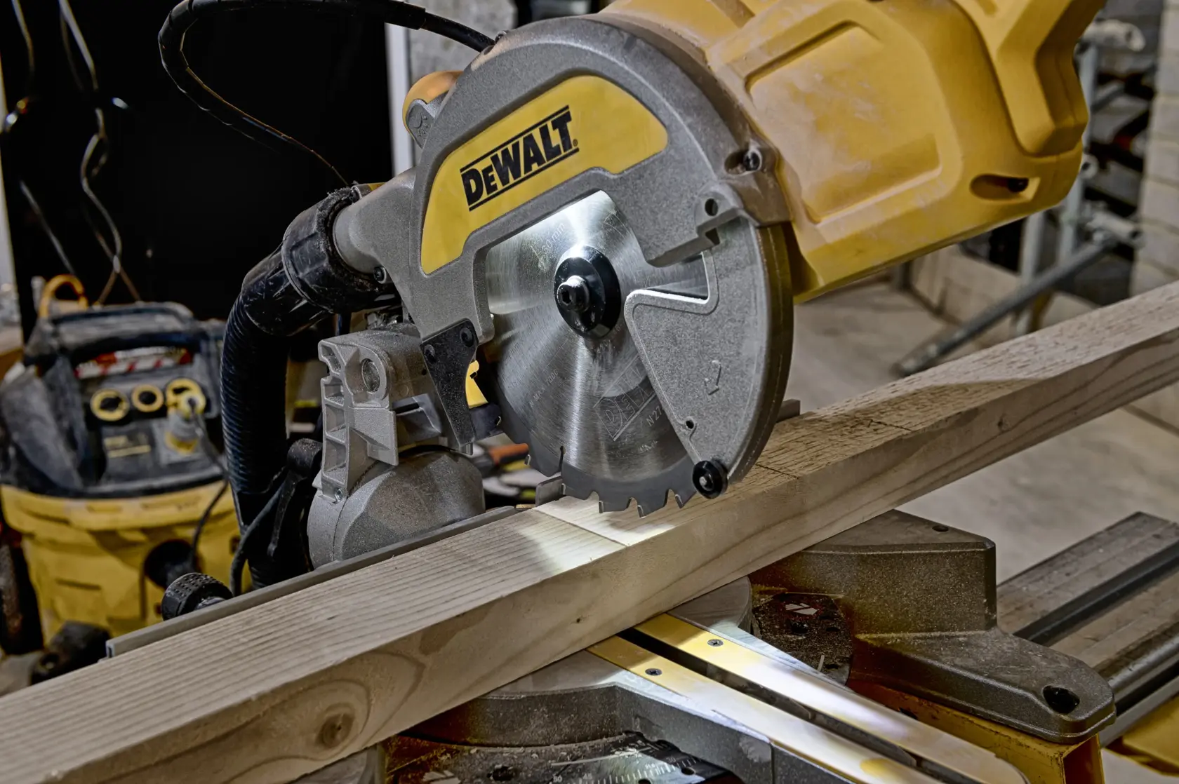 DEWALT miter saw cutting a wooden plank in a workshop setting.